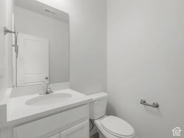 White vanity with an integrated sink, polished chrome faucet, white countertop, and a mirrored wall