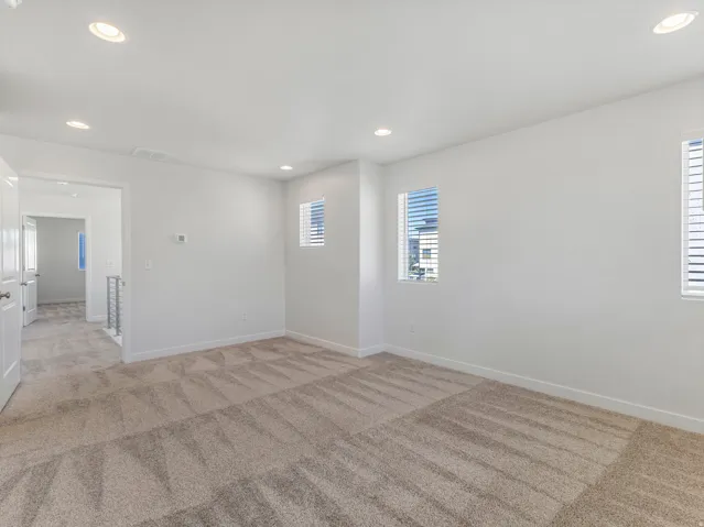 Recessed lighting, light gray carpet, multiple windows with blinds, and white walls