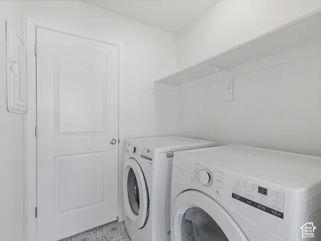 Laundry area featuring a built-in shelf, white paneled door, and patterned floor tile