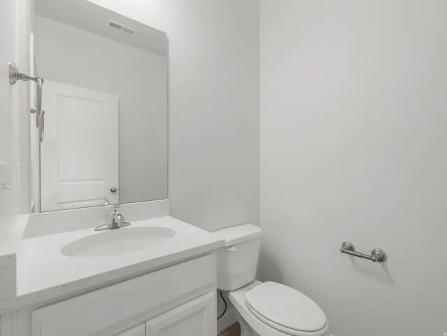 White vanity with an integrated sink, polished chrome faucet, white countertop, and a mirrored wall