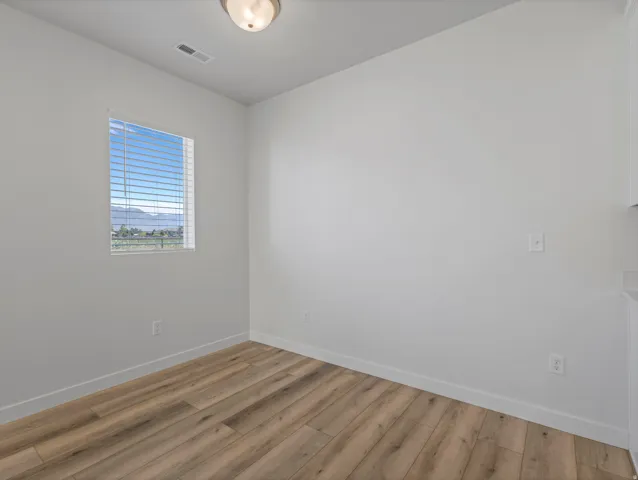 Recessed window with horizontal blinds, wood-finish flooring, white walls, and a ceiling-mounted light fixture