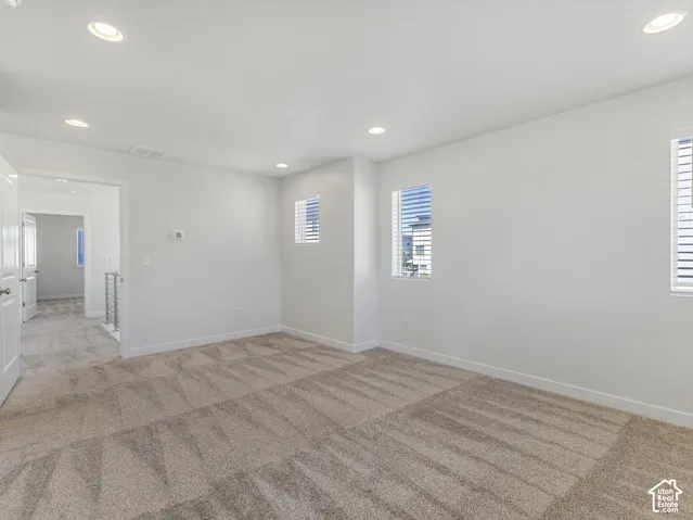 Recessed lighting, light gray carpet, multiple windows with blinds, and white walls