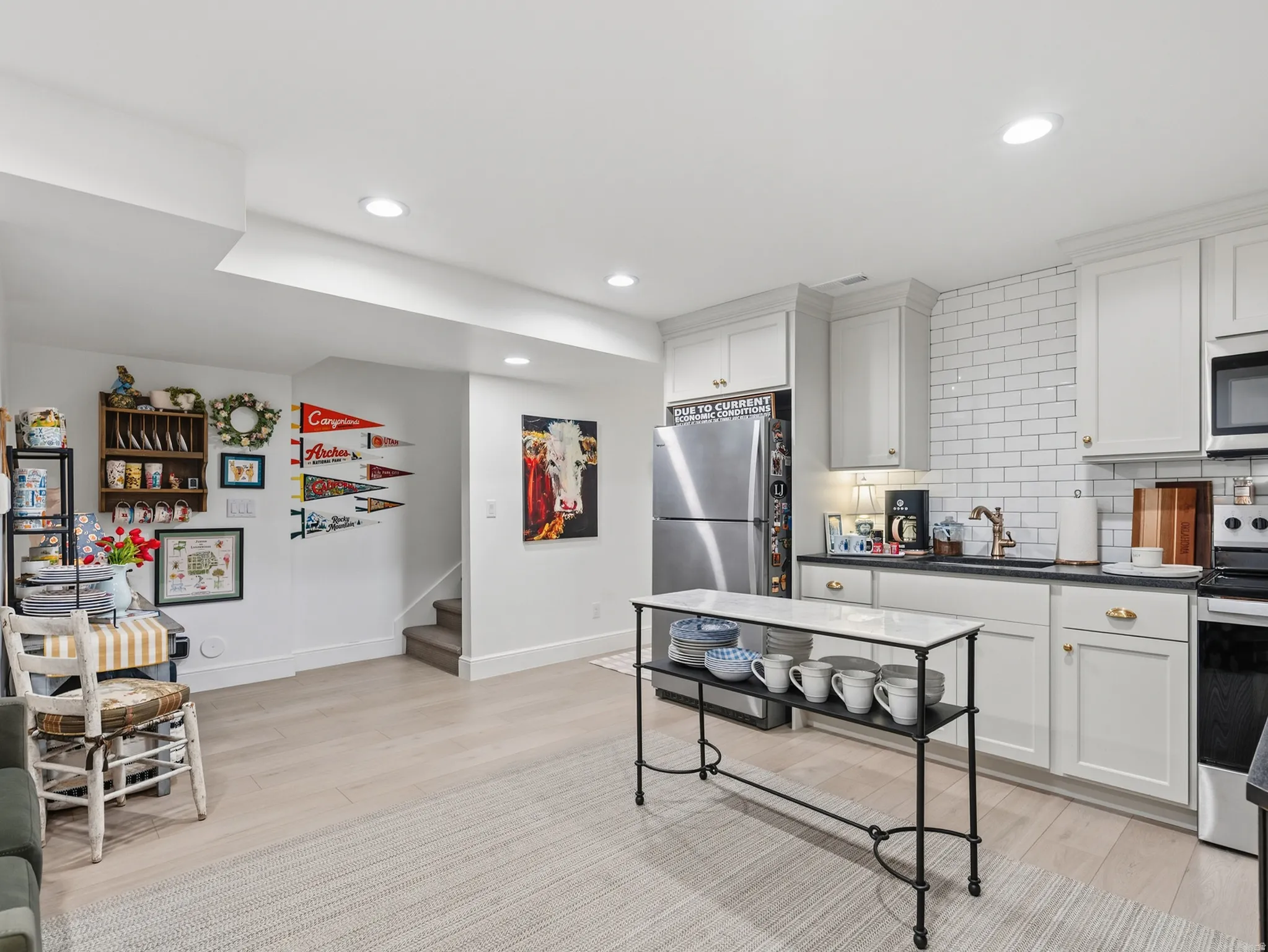 White shaker cabinetry, subway tile backsplash, stainless steel appliances, recessed lighting, and wood-finish flooring