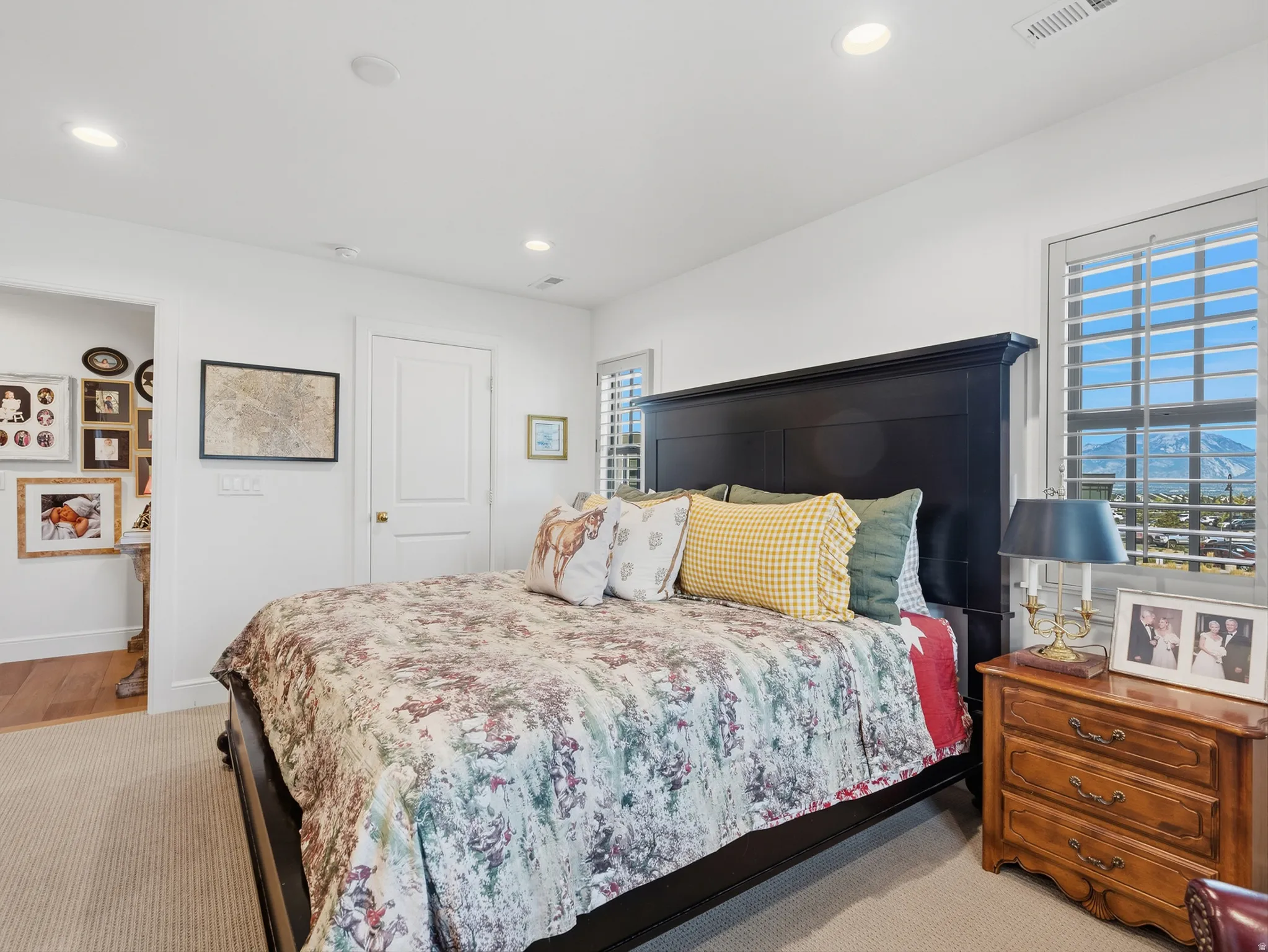 Recessed lighting, plantation shutters, white paneled door, and neutral-toned carpet flooring