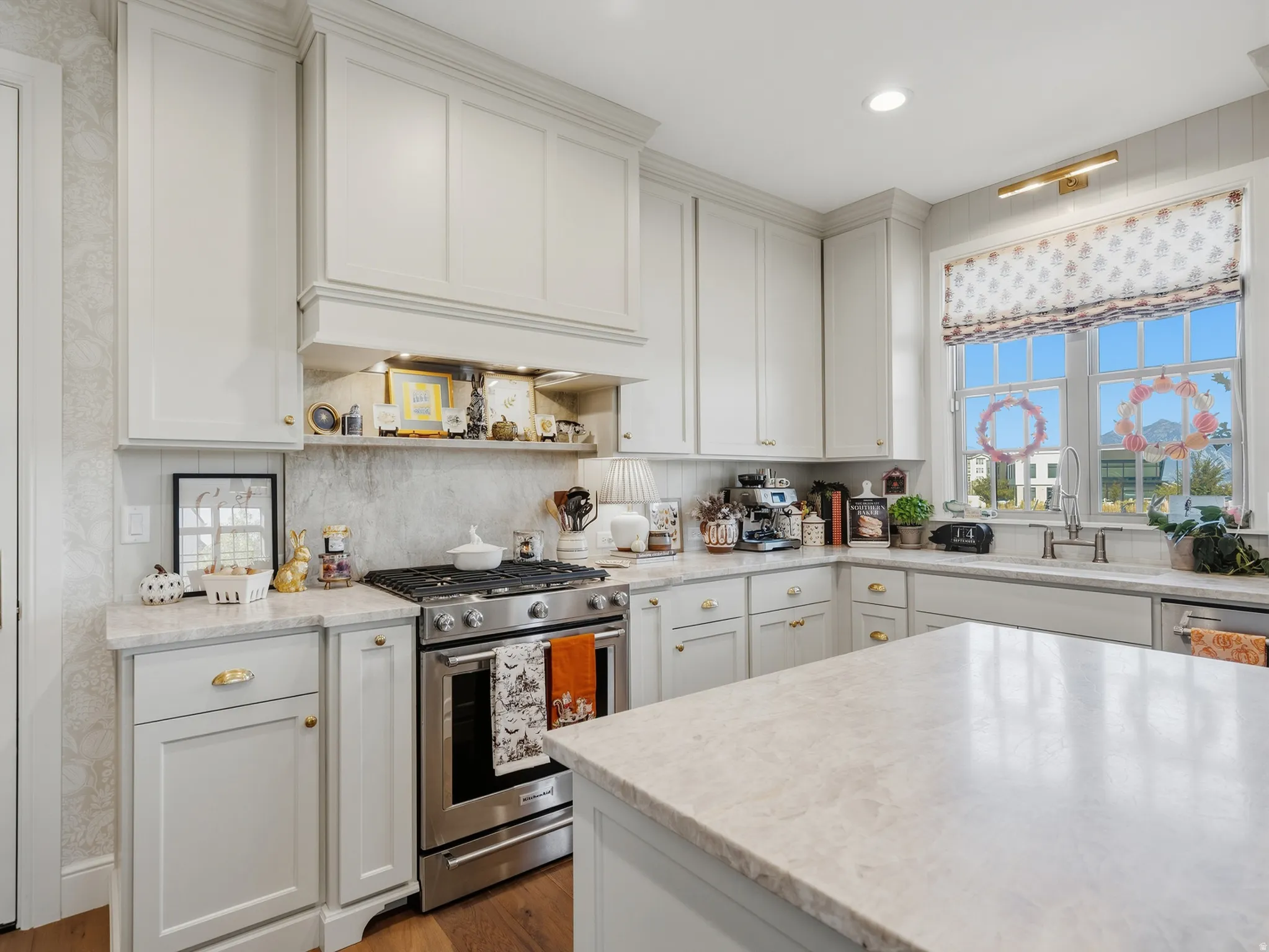 Kitchen featuring white shaker-style cabinetry, a stainless steel range, light-toned countertops, a patterned backsplash, and a window with a traditional grid pattern