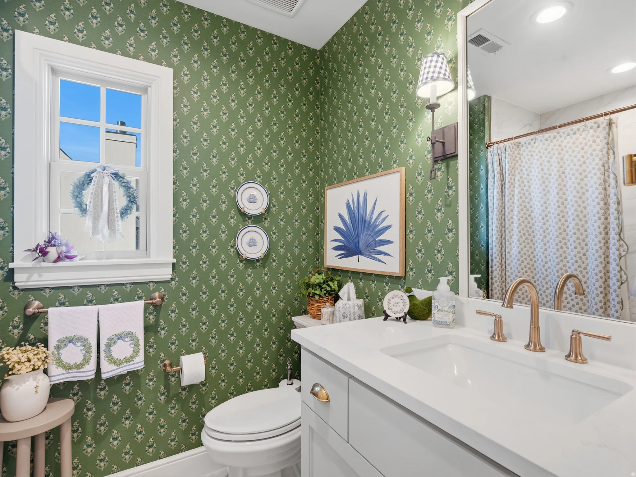 Vanity with integrated sink, bronze-finish faucet, green patterned wall covering, built-in window, and recessed lighting