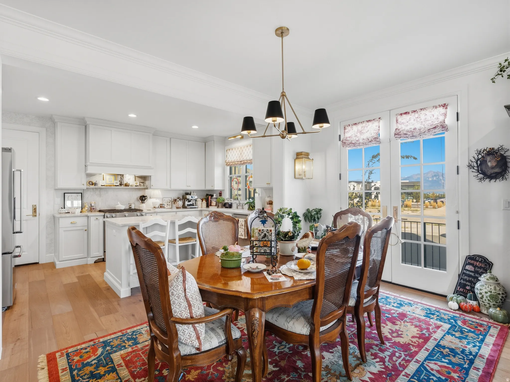 Hardwood-finish flooring, white cabinetry, island with integrated seating, and double French doors