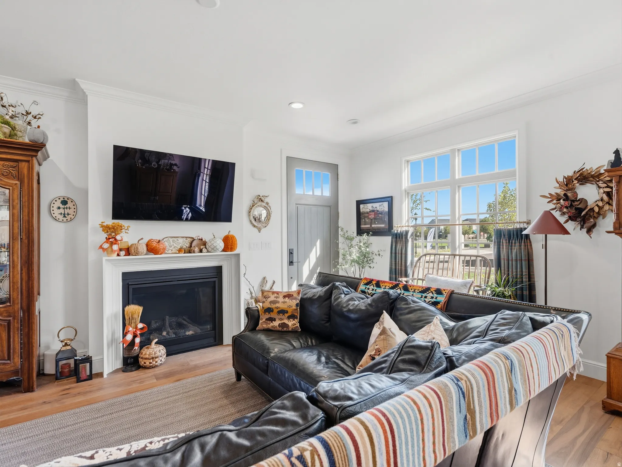 Living area featuring a fireplace with a white mantel, recessed lighting, wood-finish flooring, a multi-pane window, and a door with an upper glass panel