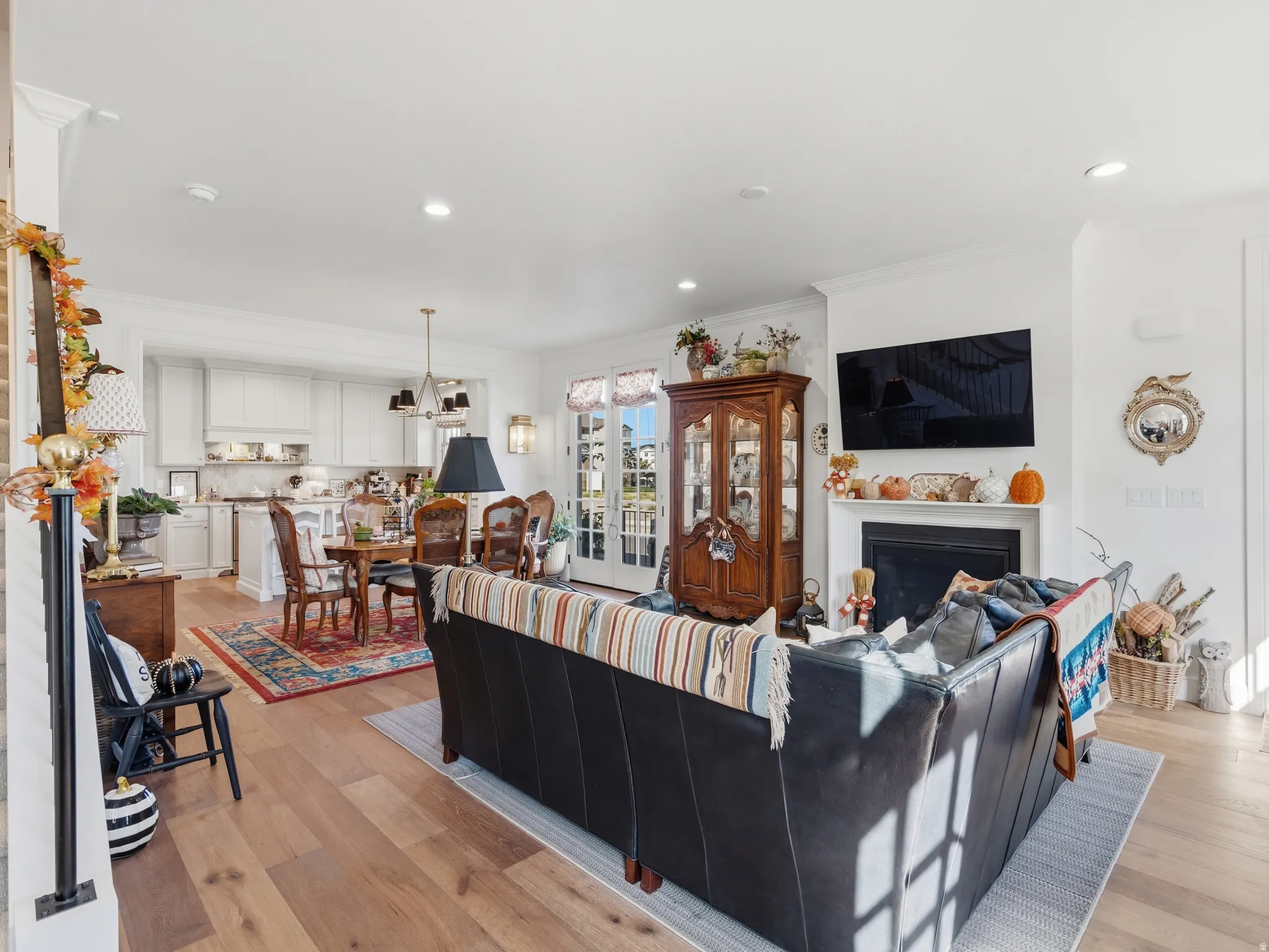 Hardwood flooring throughout, white cabinetry, integrated fireplace, recessed lighting, and French doors