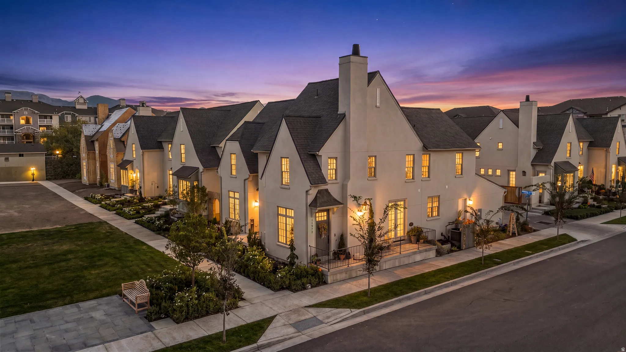 Stucco exterior with prominent gabled rooflines, multiple windows with dark trim, a covered entry porch, and a private patio space