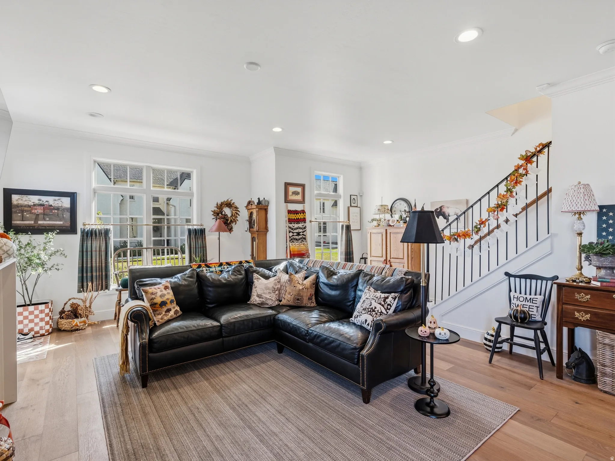 Recessed lighting, wood-finish flooring, white walls, and a staircase with black iron balusters