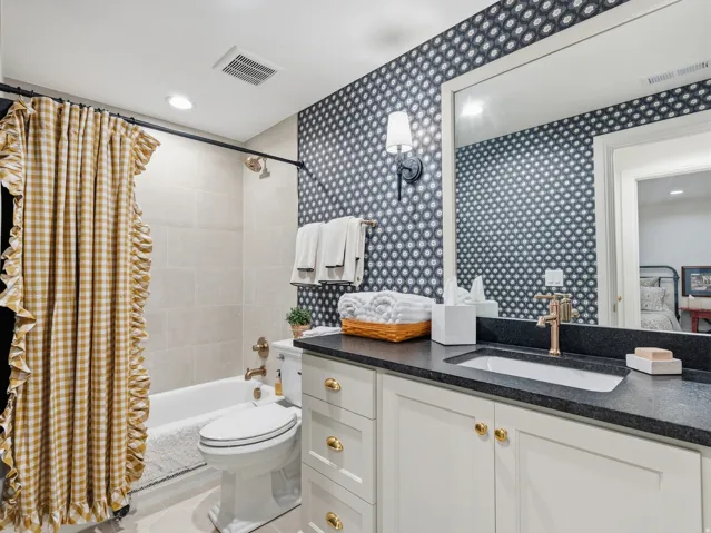 Vanity with dark countertop, integrated sink, and gold-tone faucet