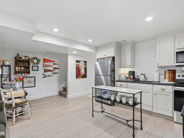 White shaker cabinetry, subway tile backsplash, stainless steel appliances, recessed lighting, and wood-finish flooring