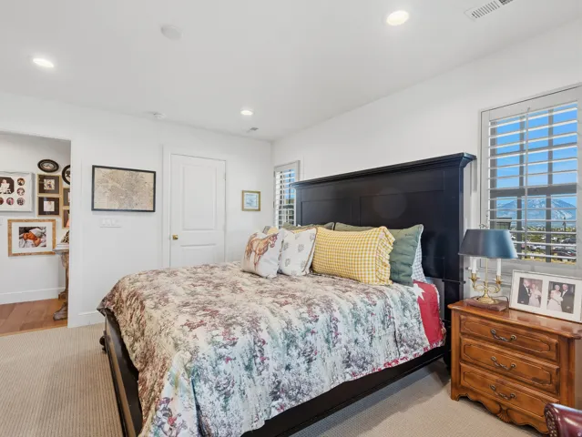 Recessed lighting, plantation shutters, white paneled door, and neutral-toned carpet flooring