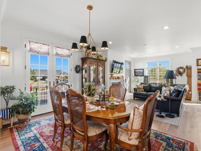 Open-concept dining area with wood-finish flooring, a brass-tone chandelier, and French doors