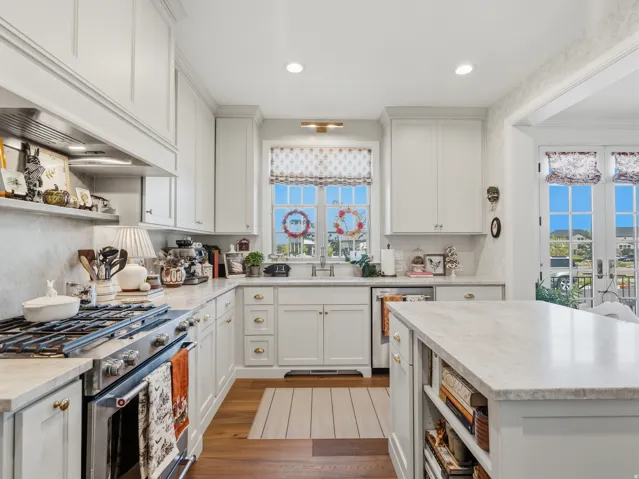Gourmet kitchen with white cabinetry, stainless steel range with hood, stone countertops, a center island, and wood-finish flooring