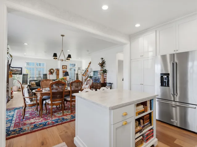 Open-concept living area featuring wood-finish flooring, recessed lighting, and a stainless steel refrigerator