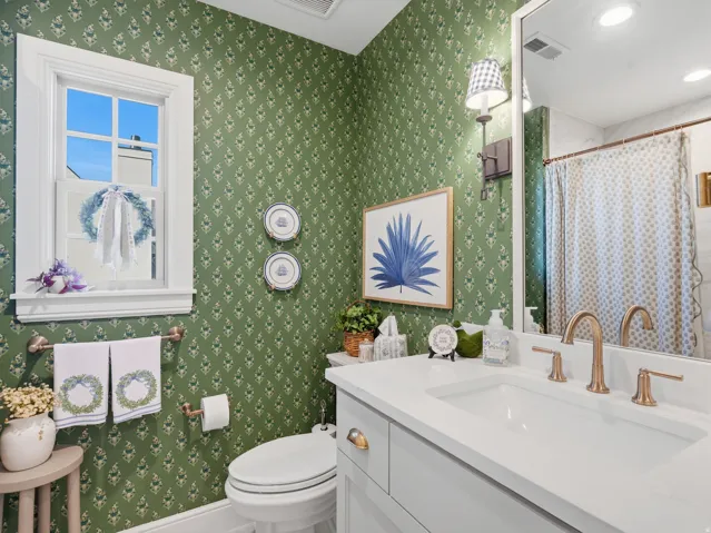 Vanity with integrated sink, bronze-finish faucet, green patterned wall covering, built-in window, and recessed lighting