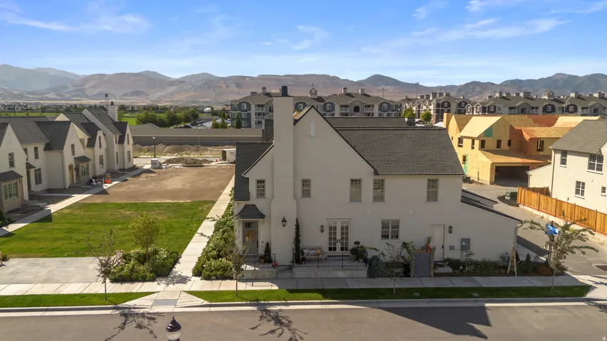 White stucco exterior with a dark shingle roof, featuring multiple windows and a prominent chimney