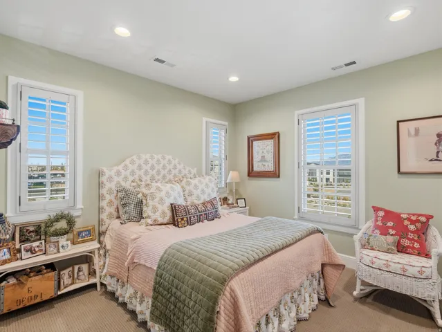 Recessed lighting, light-toned carpeting, and multiple windows with plantation shutters