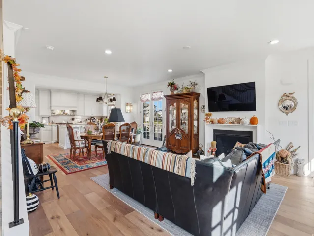 Hardwood flooring throughout, white cabinetry, integrated fireplace, recessed lighting, and French doors