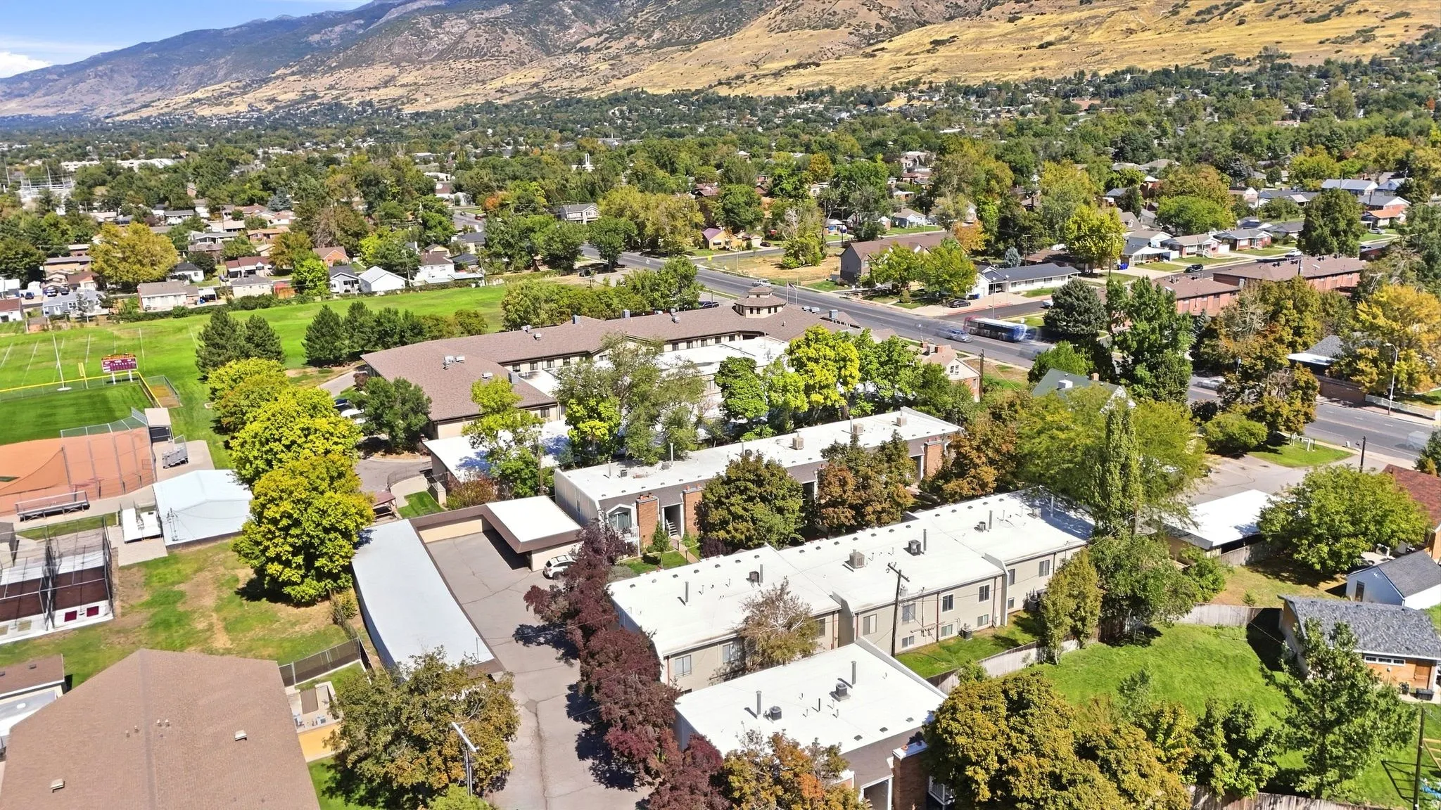Mountain backdrop, mature trees, residential properties, green spaces, paved roads