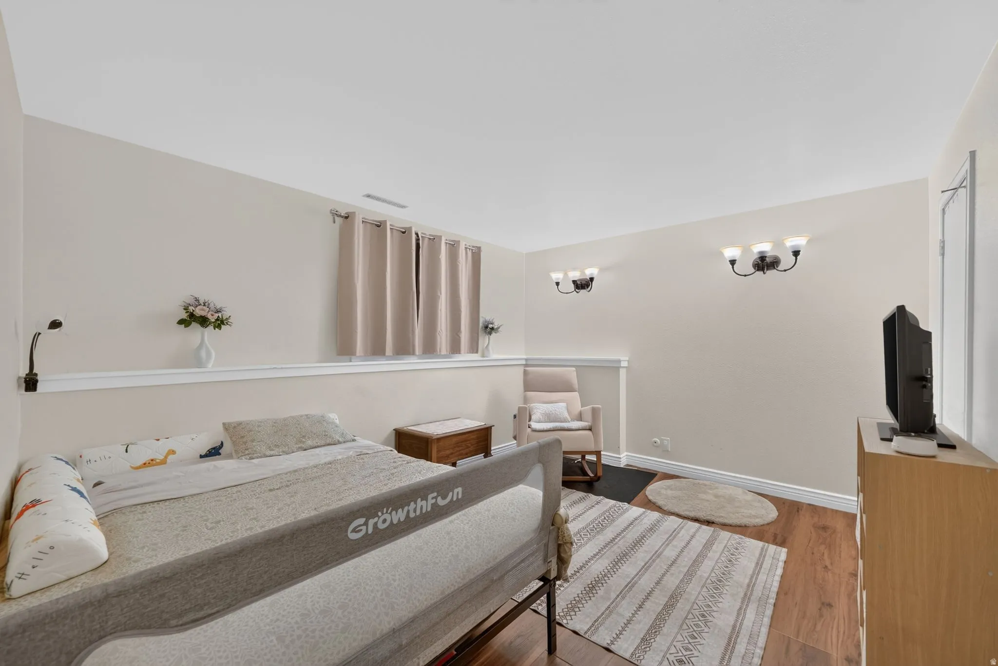 Master bedroom. Wood-finish flooring with neutral wall tones and a white chair rail