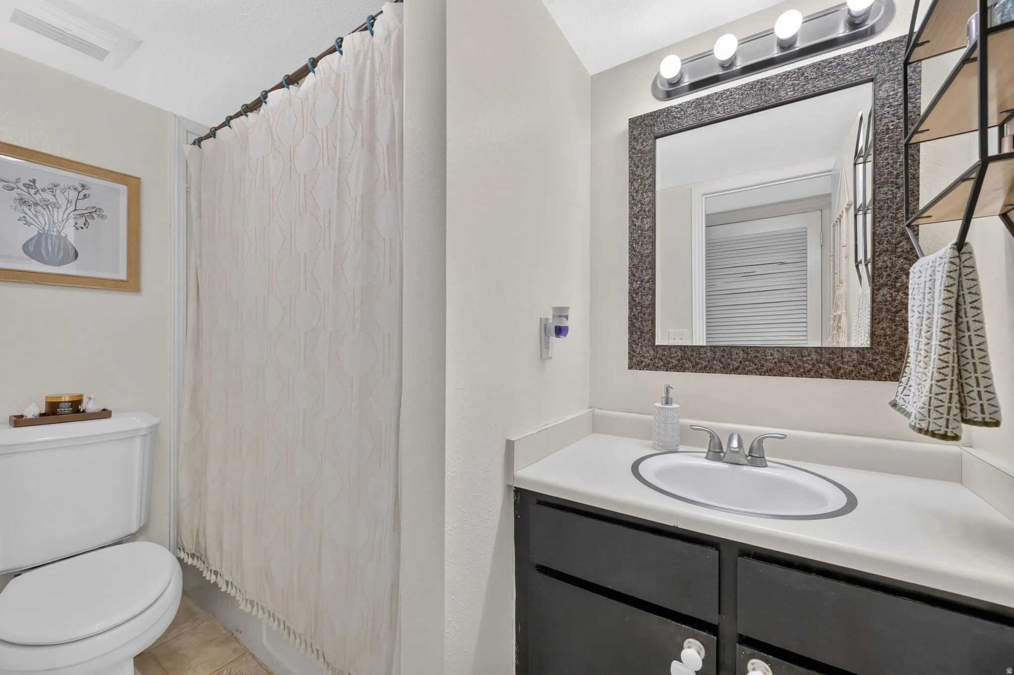 Vanity with a white countertop and dark base cabinetry, oval undermount sink, and wall-mounted light fixture