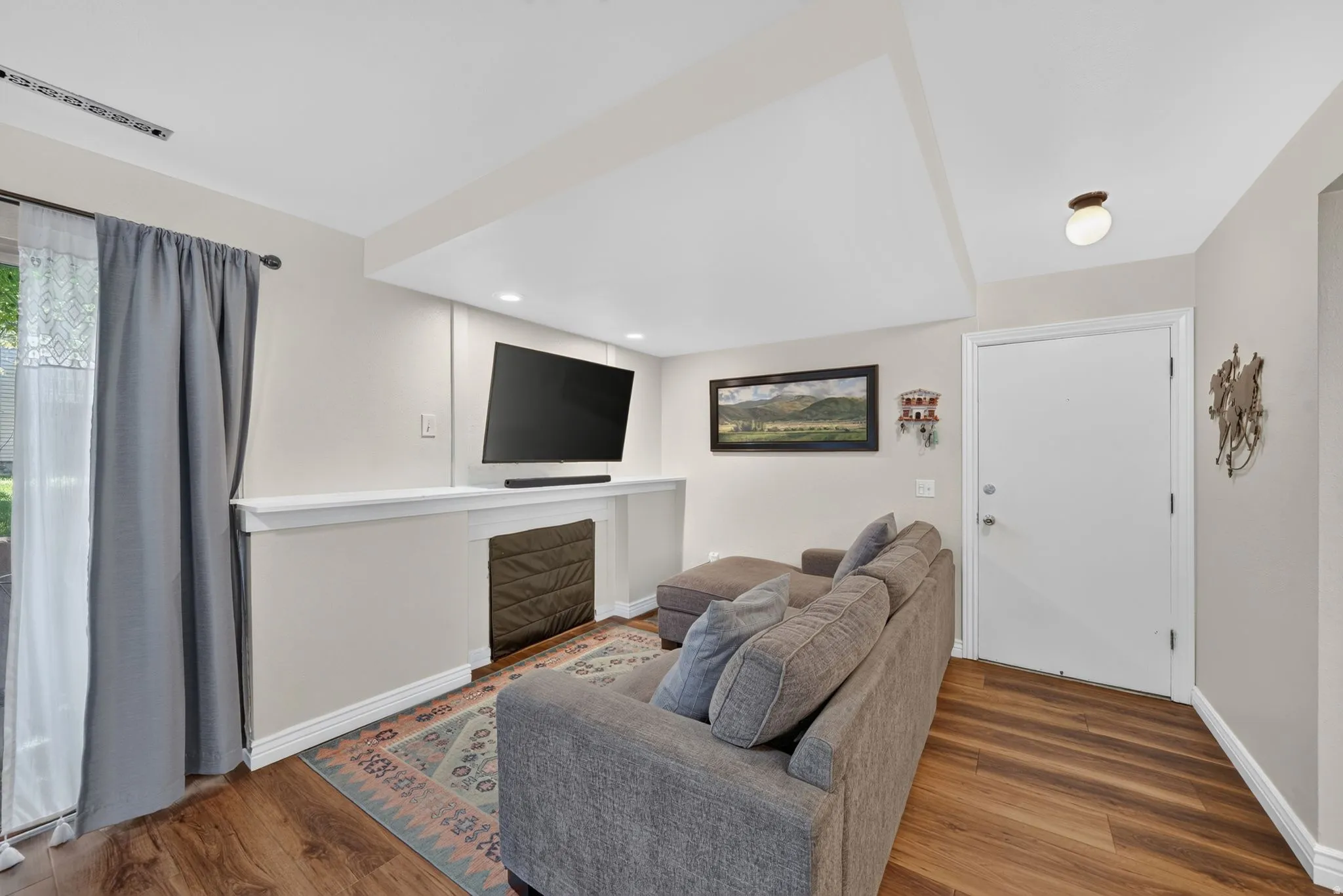 Wood-finish flooring, recessed ceiling lighting, patio access through sliding glass doors, white trim, and a white interior door