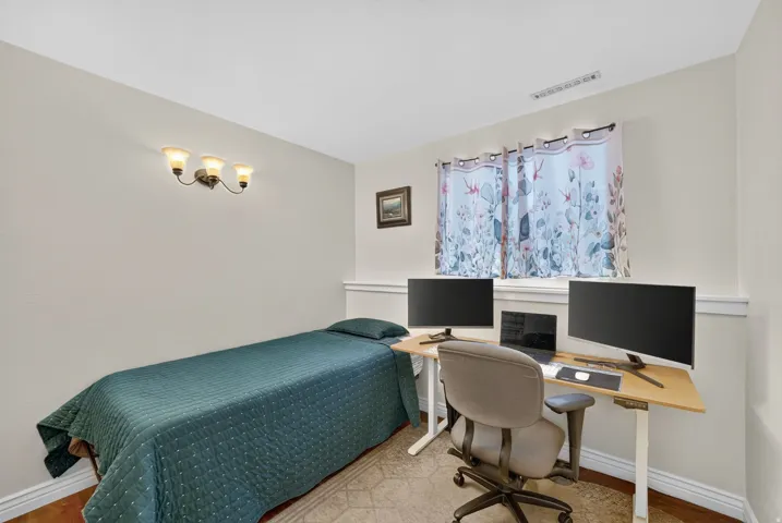 Wall-mounted light fixture, window with curtains, and wood-finish flooring