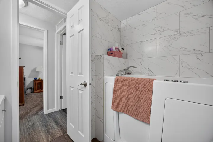 Spacious bathroom with walk-in tub. tub has shower wand, and tile surround and can be used as a shower.