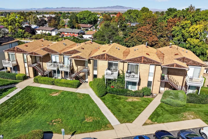 Multi-level brick exterior with balconies, exterior staircases, and a surrounding green space.