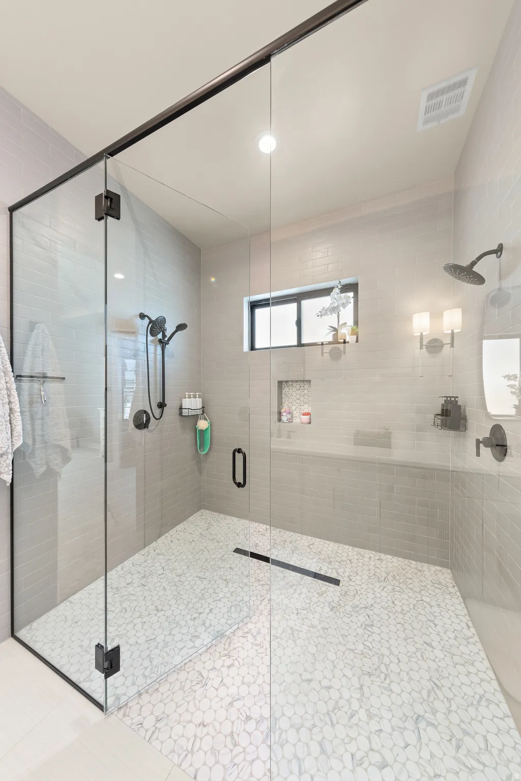 Glass-enclosed shower featuring a linear drain and pebble-tile flooring