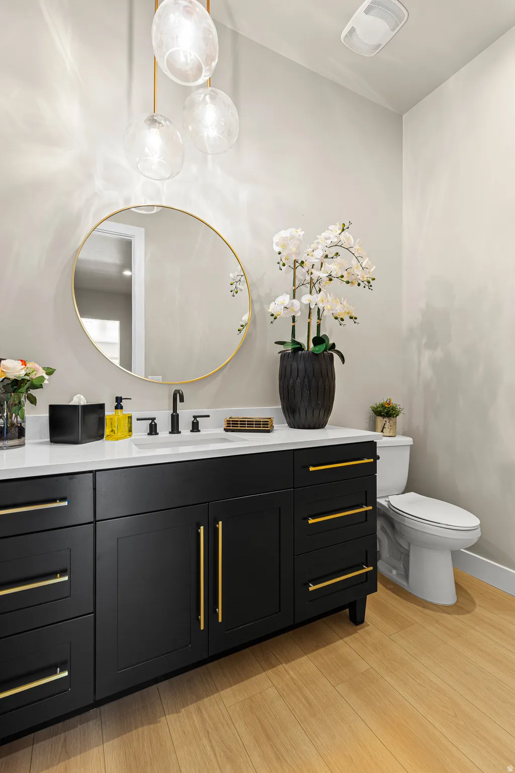 Black vanity with gold hardware, white countertop, undermount sink, and black wall-mounted faucet