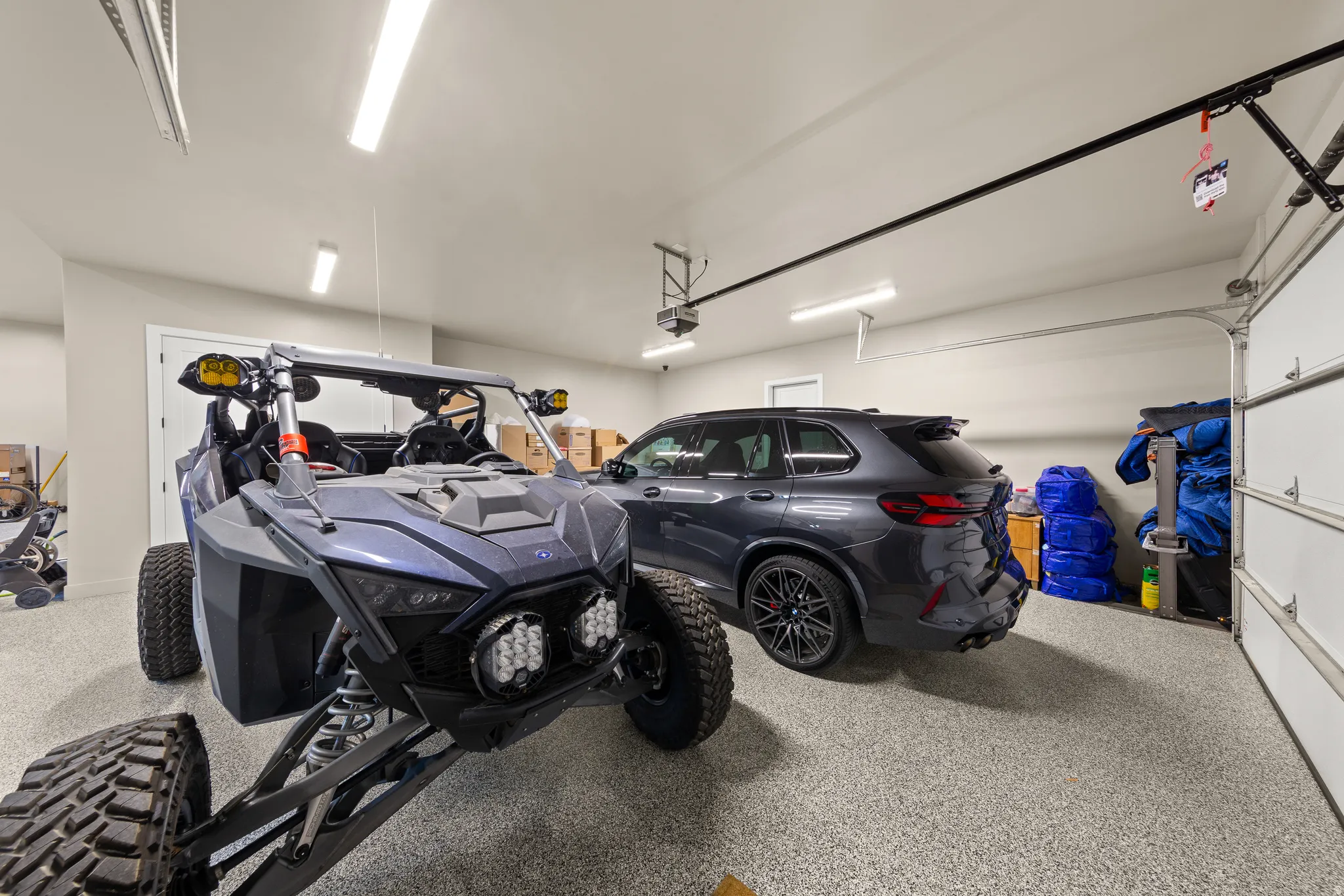 Garage with epoxy-coated flooring, multiple overhead light fixtures, and a white overhead garage door