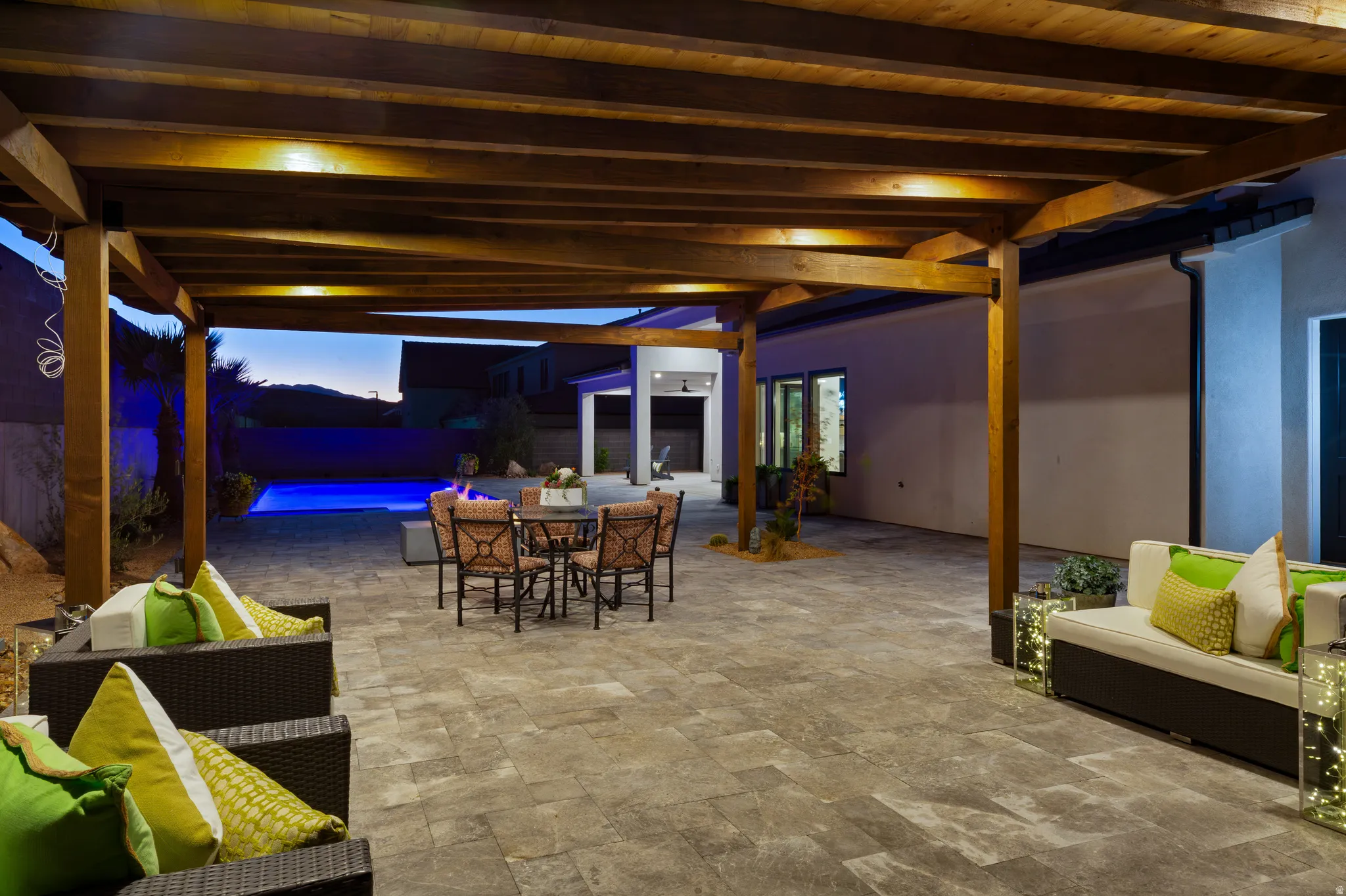 Spacious outdoor living area with a wood pergola, expansive paved patio, built-in swimming pool, and dedicated fire pit