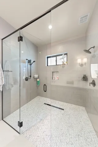Glass-enclosed shower featuring a linear drain and pebble-tile flooring