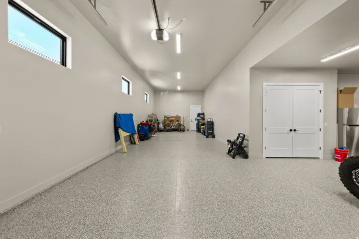 Expansive garage with an epoxy floor finish, multiple windows, and recessed lighting