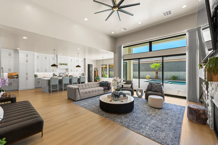 High ceilings, wood-finish flooring, full-height white cabinetry, kitchen island with seating, and sliding glass doors opening to a private pool