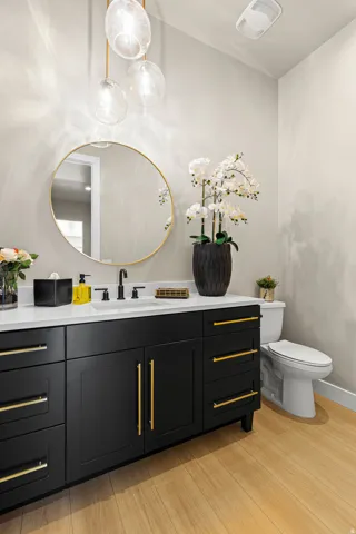 Black vanity with gold hardware, white countertop, undermount sink, and black wall-mounted faucet