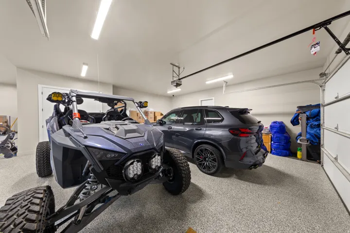 Garage with epoxy-coated flooring, multiple overhead light fixtures, and a white overhead garage door