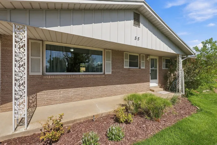 Brick exterior with white trim, covered front entry, decorative porch columns, and established landscaping
