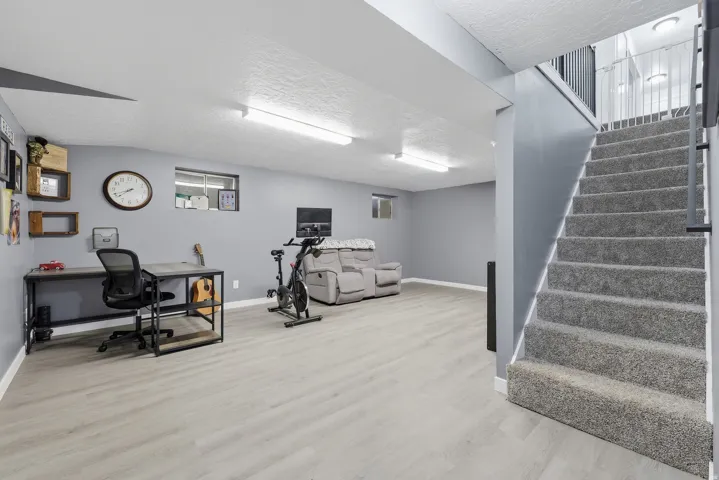 Finished lower level featuring light wood-finish flooring, recessed windows, and overhead strip lighting
