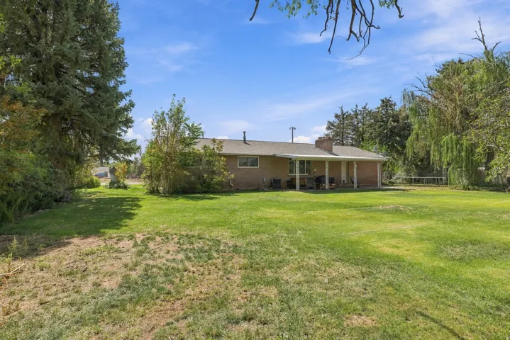 Expansive green lawn with mature trees and a covered patio area