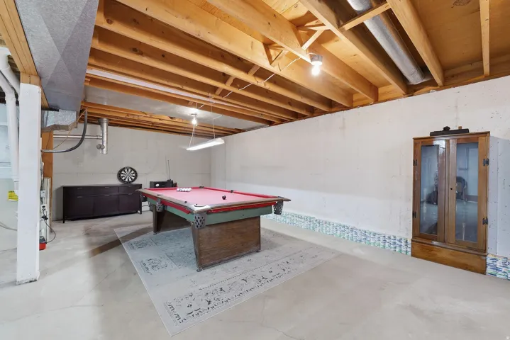 Unfinished room with exposed wood beam ceiling with recessed lighting