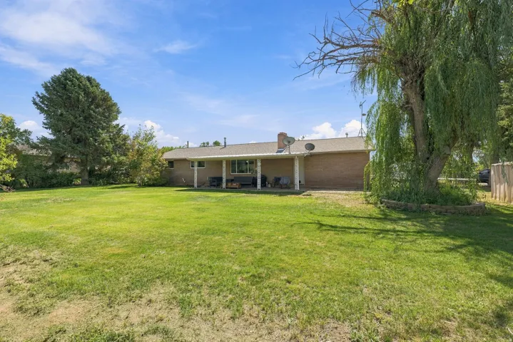 Expansive lawn with mature trees and a covered patio area