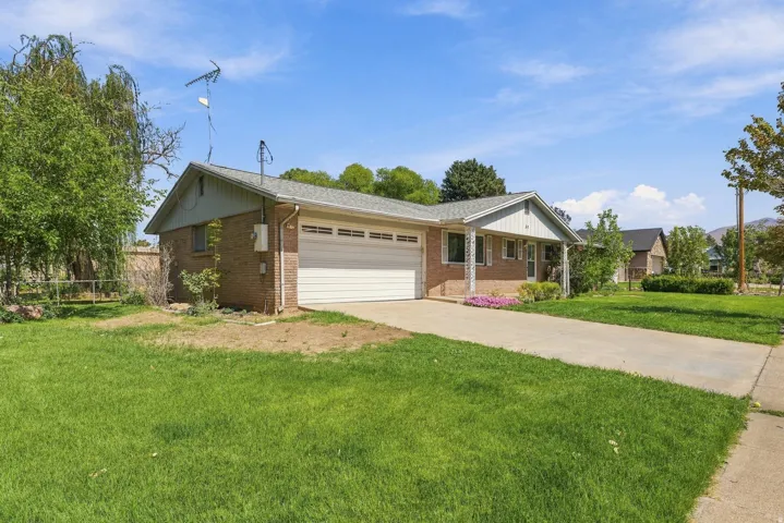Brick exterior with an attached garage, covered entryway, and a paved driveway