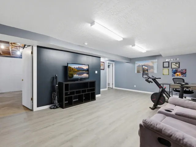 Spacious finished lower level with light wood-finish flooring, recessed lighting, and a dedicated storage area