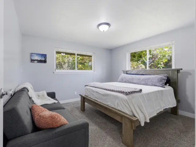 Guest bedroom with light gray walls, two windows, and a flush-mount ceiling light fixture