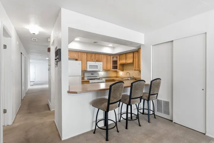 Kitchen pass-through with breakfast bar, wood cabinetry, built-in microwave, and stainless steel sink
